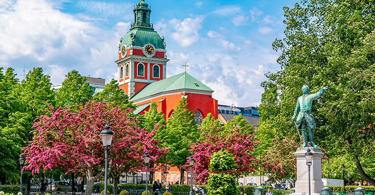 Kościół Riddarholmen i okoliczna architektura na wyspie Riddarholmen w Sztokholmie pod błękitnym niebem.