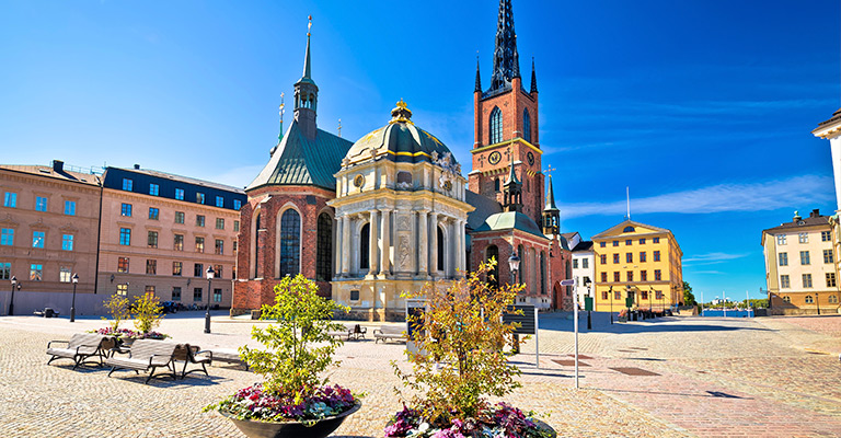 Kościół Riddarholmen i okoliczna architektura na wyspie Riddarholmen w Sztokholmie pod błękitnym niebem.