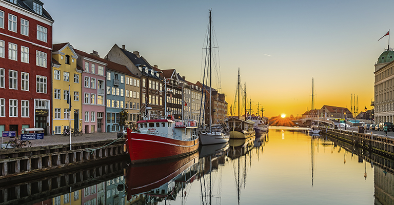 Kolorowe kamienice wzdłuż kanału Nyhavn w Kopenhadze o zachodzie słońca. Malownicze miejsca w Kopenhadze.