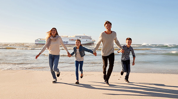 Family walking on the beach with TT-Line Green Ship in the background.