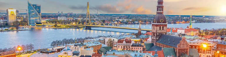 Utsikt över centrala Riga med floden Daugava och den upplysta Vansu-bron i skymningen – en del av rundresan Vilnius–Riga–Klaipėda.